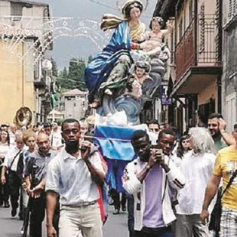 Statua della Madonna portata a spalla da tre immigrati