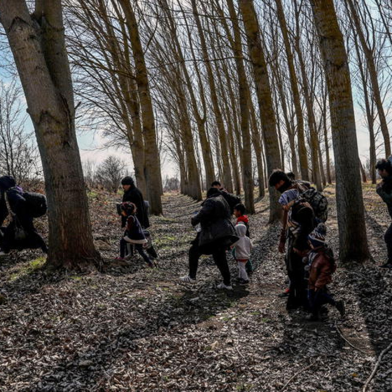 epa08262374 A group of migrants with children walks into a wood near the Meric (Evros) River at the Turkish-Greek border, in Edirne, Turkey, 01 March 2020. Thousands of refugees and migrants are gathering on the Turkish side of the border with Greece with the intent to cross into the European Union following the Turkish government's decision to loosen controls on migrant flows after the death of 33 Turkish soldiers killed in an attack in Idlib, Syria on 27 February. EPA/SEDAT SUNA