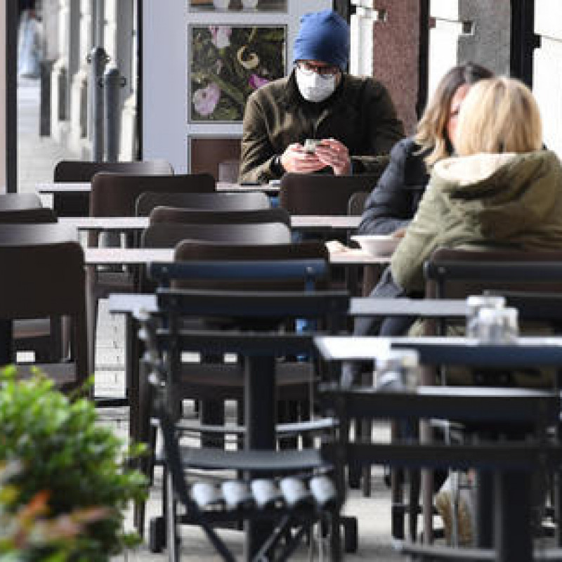 A person, wearing a face mask, takes advantage of the sunny day by checking his smartphone while having lunch in the semi-deserted terrace of a restaurant in the center of Milan, Italy, 27 October 2020. Smartworking, now used by many companies as a Covid containment measure, is impacting dramatically on the catering economy.ANSA/DANIEL DAL ZENNARO