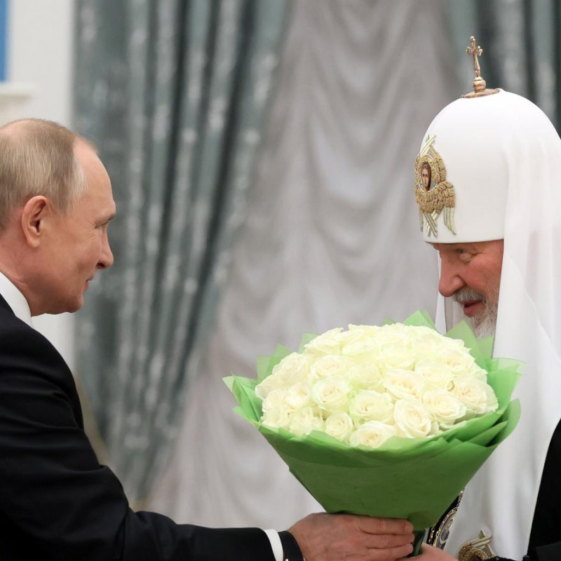 Il presidente russo Vladimir Putin, a sinistra, porge un mazzo di fiori al patriarca della Chiesa ortodossa russa Kirill