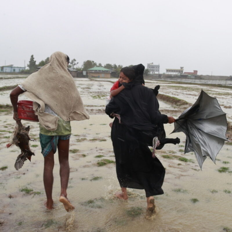 epa10627475 A family walks along with their goods during cyclone Mocha's landfall at the Shahpori Dwip, Teknuf area near Cox's Bazar, Bangladesh, 14 May 2023. Powerful cyclone Mocha made landfall mainly in Myanmar tearing the roofs and also made effect at the Bangladesh-Myanmar border line. EPA/STR