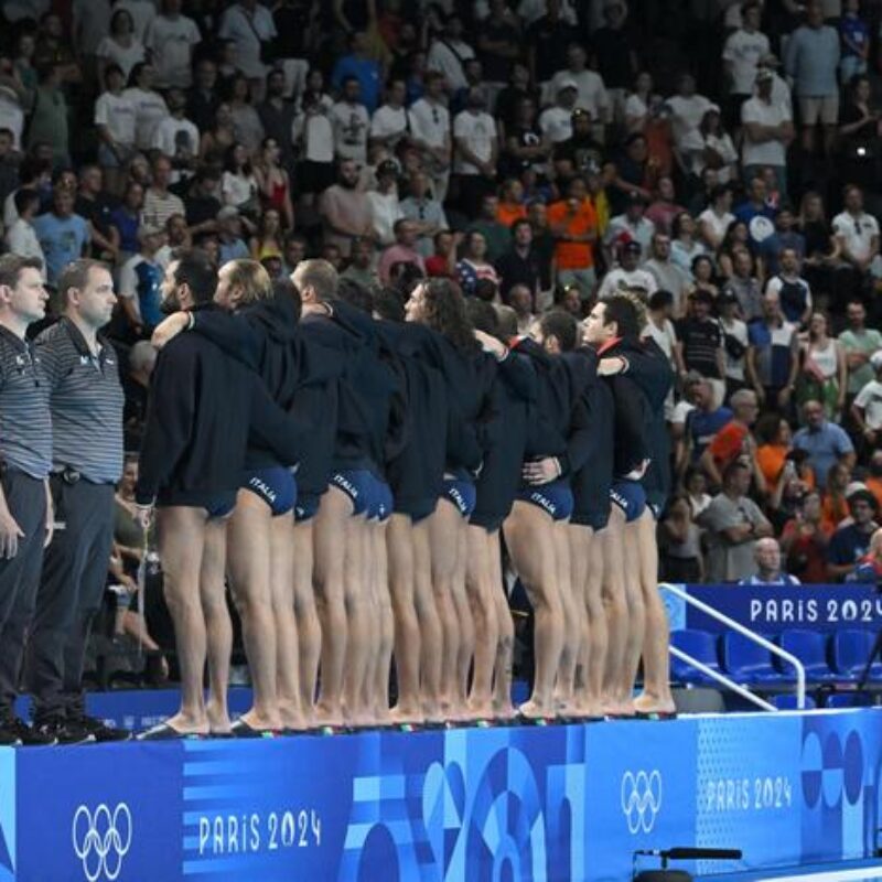 Italy's team players turn their back during the anthem to protest against the refereeing of their last match against Hungary, before the men's water polo 5th-8th classification match between Italy and Spain at Paris 2024 Olympic Games at the Paris La Defense Arena in Paris on August 9, 2024. (Photo by Andreas SOLARO / AFP)