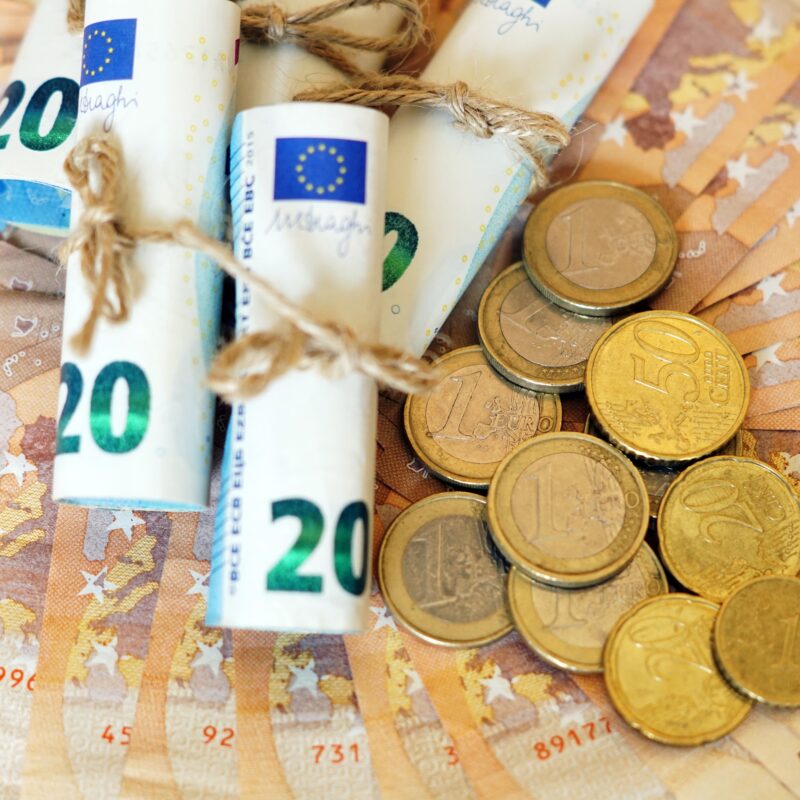 A high angle shot of some rolled banknotes and coins on more banknotes