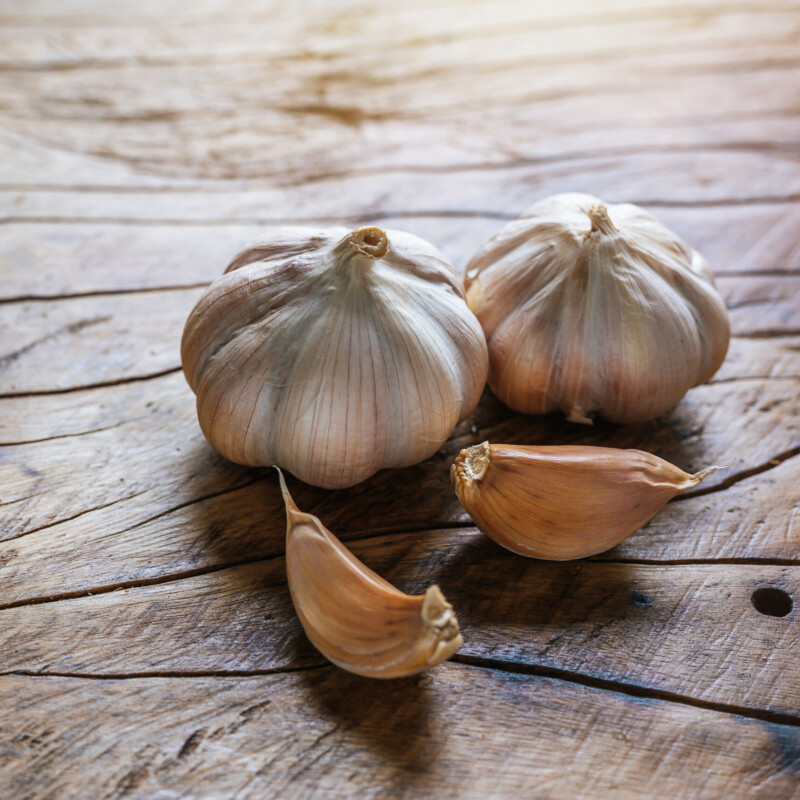 White garlic placed on a dark brown wood floor.