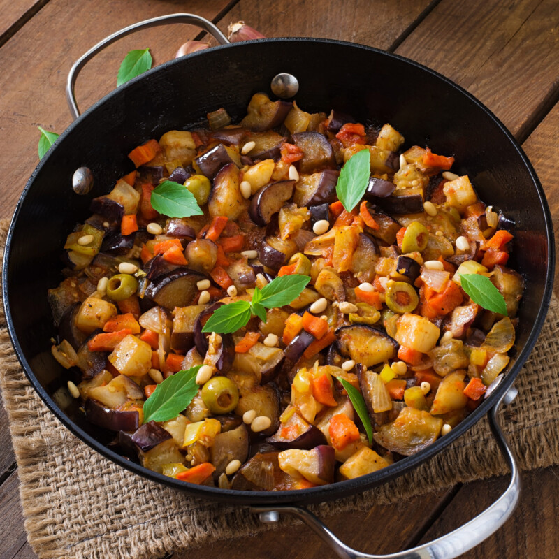 Italian Caponata with frying pan on a wooden background