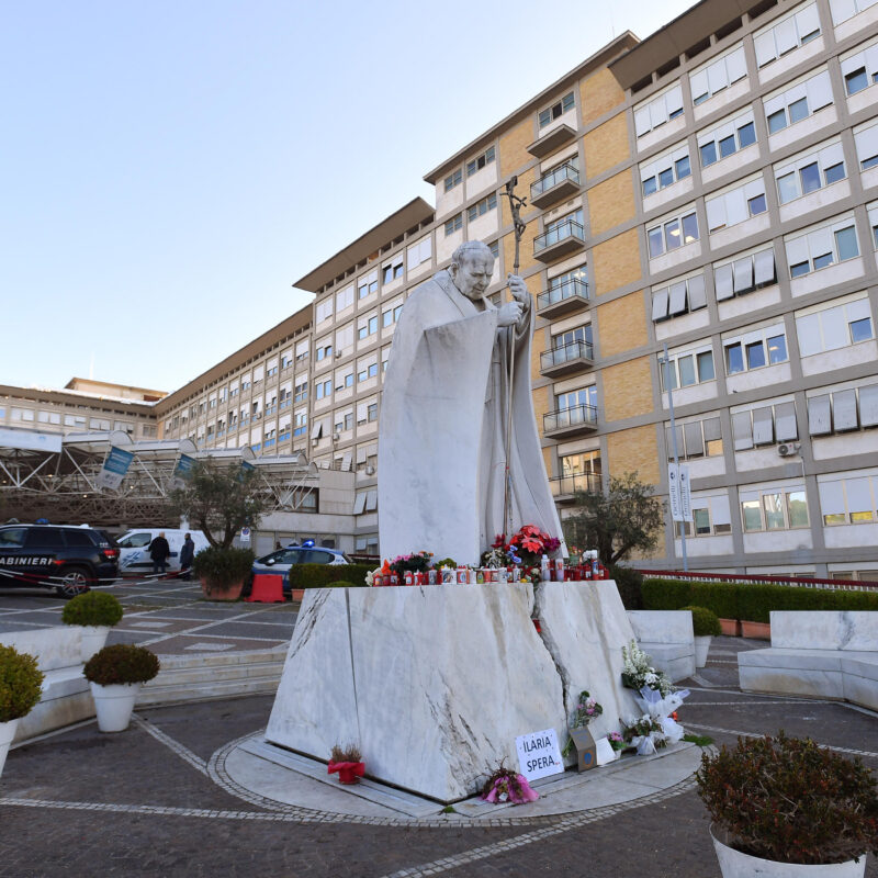 Flowers and candles are laid at the foot of a statue of Pope St. John Paul II outside the Gemelli University Hospital, where Pope Francis is hospitalized for tests and treatment for bronchitis, in Rome, Italy, 21 February 2025. Pope Francis was hospitalized on 14 February due to a respiratory tract infection.ANSA/FABIO CIMAGLIA