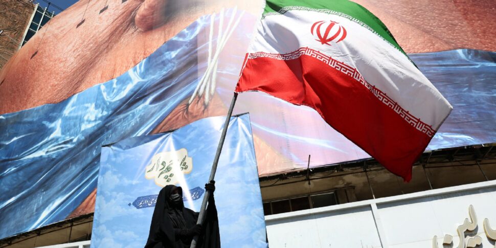 https://assets.gazzettadelsud.it/2026/05/A-veiled-woman-holds-Irans-national-flag-in-front-of-a-huge-anti-US-billboard-referring-to-US-President-Donald-Trump-and-the-Strait-of-Hormuz-at-Valiasr-Square-in-Tehran-Iran-970x485.jpg