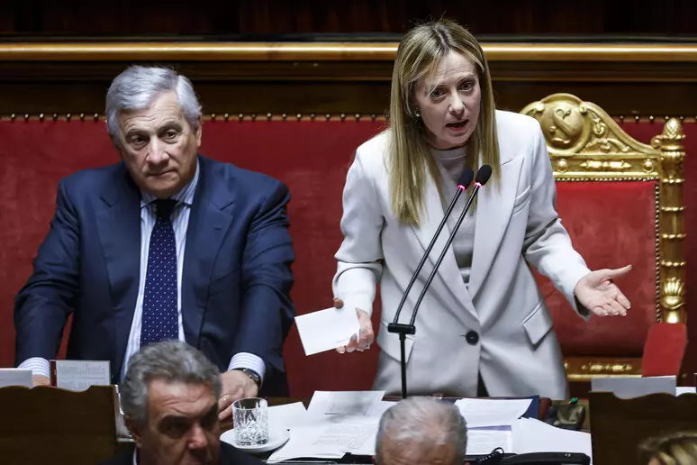 Aula di Montecitorio con deputati in discussione, cartelli di protesta esposti dai banchi dell'opposizione durante il voto